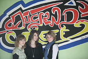 Drei Mädchen stehen vor einer Wand mit der Aufschrift "Jugendtreff"
