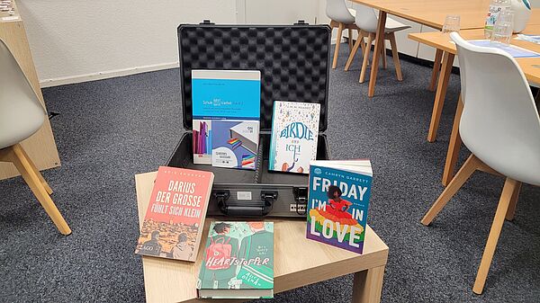 Bücherkoffer Ansichtsexemplar für die Klassenstufen Sek I. Enthält sichtbar: Darius der Große, Heartstopper, Friday I'm in Love, Birdie und ich - sowie die Handreichung "Schule lehrt/lernt Vielfalt Bd. 2" und das "Queere Glossar"